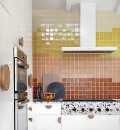 a kitchen with orange and yellow tiles on the walls