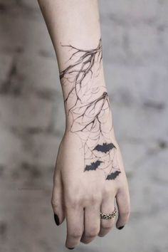 a woman's hand with a tattoo on it and bats flying around the wrist