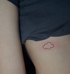 a woman's thigh with a small cloud tattoo on it