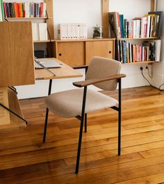 a chair sitting in front of a desk with a book shelf and books on it