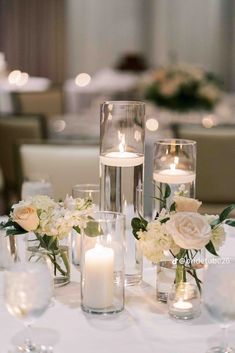 the centerpieces on this table are filled with flowers, candles and glass vases