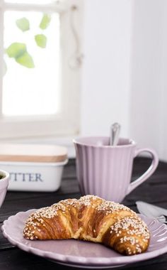 a croissant sitting on a plate next to a cup and saucer