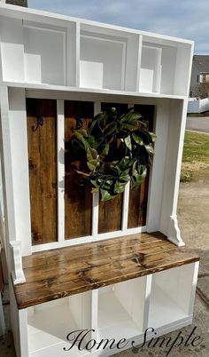 a white shelf with a wreath on top of it and some shelves behind it that are made out of wood