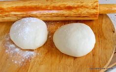 two doughnuts sitting on top of a wooden cutting board next to a rolling pin