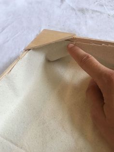 a hand pointing at the edge of a piece of cardboard