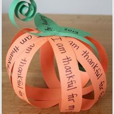 an ornament made out of orange paper with words written on it and a green ribbon