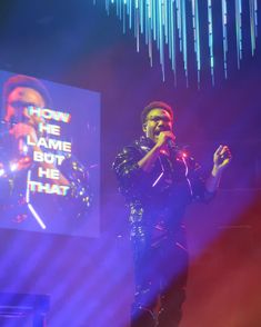 a man standing on top of a stage holding a microphone in front of a screen