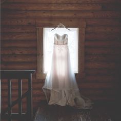 a wedding dress hanging in front of a window