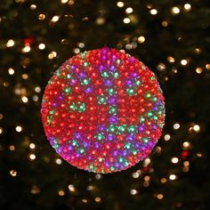 a lighted christmas ornament in front of a tree with lots of lights on it