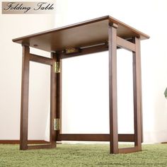 a small wooden table sitting on top of a green carpeted floor next to a potted plant