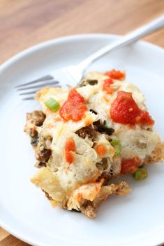 a white plate topped with lasagna covered in cheese and tomato sauce next to a fork