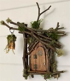 a fairy house made out of branches with moss growing on the roof and door to it