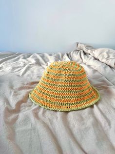 a yellow crocheted hat sitting on top of a bed