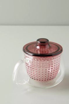 a glass tea pot with a lid and strainer