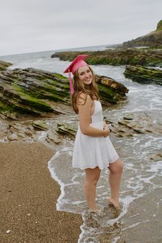 a girl in a white dress standing on the beach