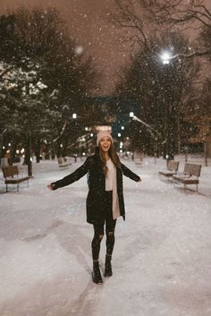 a woman standing in the snow with her arms outstretched