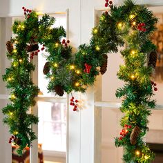 two christmas wreaths with lights hanging from them on a window sill in front of a door