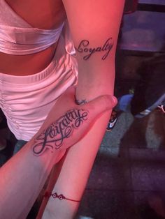 two girls with matching tattoos on their arms