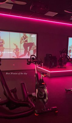 there is a gym room with exercise equipment on the floor and two large screens in the wall