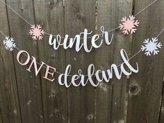 a sign that says winter onederland hanging on a fence with snowflakes