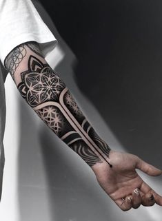 a man's arm with an intricate tattoo design on the left forearm and hand