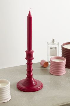 a pink candle sits on a table next to other candles