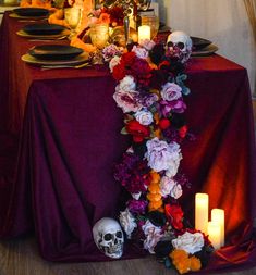 the table is set with candles, flowers and skulls for halloween dinner party decorating