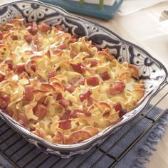 a casserole dish with bacon and cheese in it on a cooling rack next to a blue towel