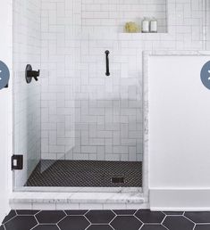 a black and white bathroom with hexagonal tiles on the floor, an open shower door