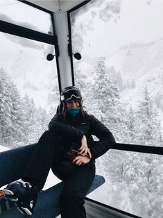 a woman sitting on top of a ski lift wearing a face mask and goggles