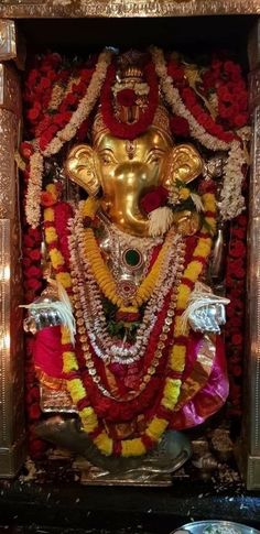 an idol is displayed in the middle of a room with red and yellow garlands