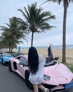 a woman sitting on the hood of a pink sports car