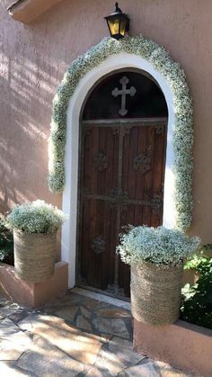 two potted plants are in front of a church door with a cross on it