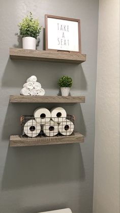 bathroom shelves with toilet paper and towels on them in the corner, along with a sign that says take seat