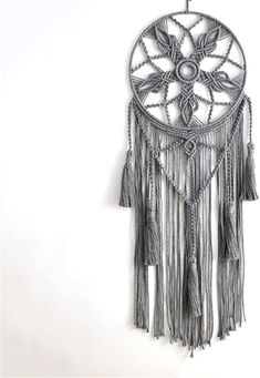 a metal wall hanging with tassels and beads on the outside, in front of a white background