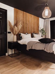 a bedroom with black and white bedding, wooden headboard, pillows and rugs