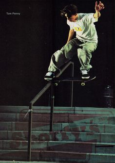 a man riding a skateboard down the side of a metal hand rail in front of stairs