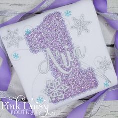 a purple and white snowflaked square with the letter j on it's side