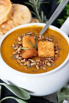 a white bowl filled with soup and croutons on top of toasted bread