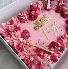 a pink birthday cake in a box decorated with flowers and gold lettering that says happy 90th