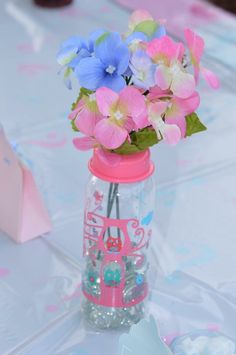 there is a vase with flowers inside of it on the tableclothed table cloth