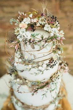 a three tiered wedding cake with flowers and leaves on the top, sitting on a table