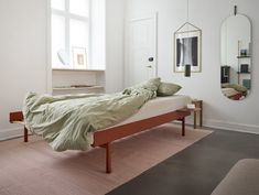 a bed sitting in a bedroom next to a wall mounted mirror and a wooden bench