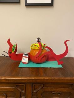 a wooden table topped with an orange and red sculpture