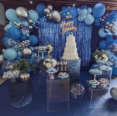 a blue and silver birthday party with balloons, cake and desserts on the table