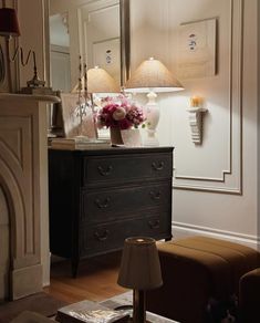 a living room with a dresser, mirror and lamp on the side table in front of it