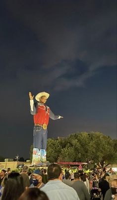 a large statue in the middle of a crowd with people around it at night time