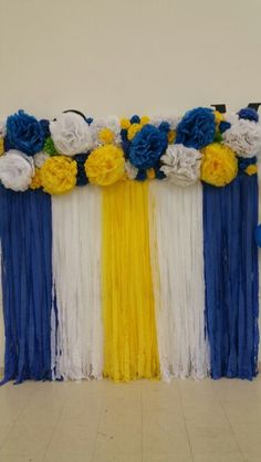 an arrangement of blue, yellow and white streamers with flowers on the top are ready to be used as a backdrop