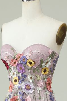 a pink dress with flowers on it and buttons in the back, sitting on a mannequin