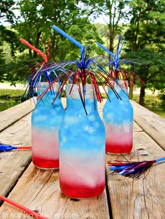 three red, white and blue drinks sitting on top of a wooden table